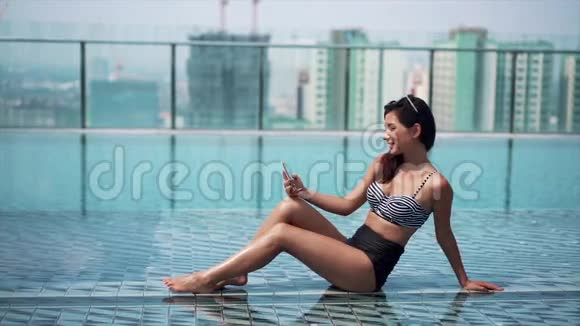 在泳池边用智能手机的漂亮女人视频的预览图