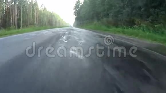 在铺好的公路上穿过森林的车辆视频的预览图