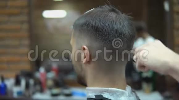 年轻理发师给理发店里有魅力的男人理发视频的预览图