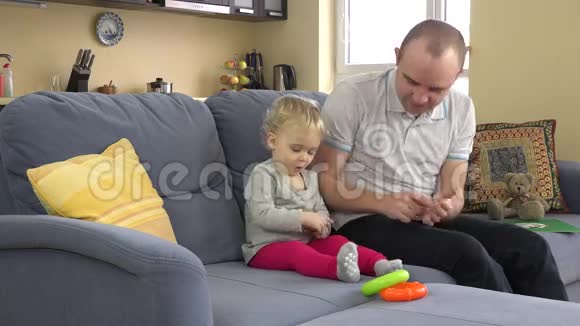 活泼的父亲在家里和小女孩在沙发上玩得很开心男人挠痒痒蹒跚学步的女孩视频的预览图