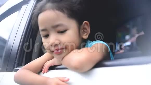 可爱的泰国亚洲小女孩她从白色的汽车里探出头来微笑着挥手问好视频的预览图