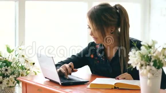 年轻漂亮的女学生坐在室内的咖啡馆里写书视频的预览图