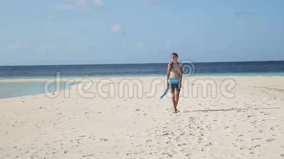 穿着丝绸长袍的女孩在海滩上散步视频的预览图