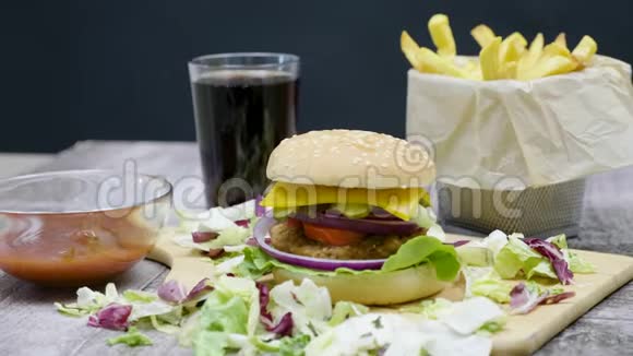 汉堡炸薯条可乐和番茄酱放在黑色背景的木桌上视频的预览图