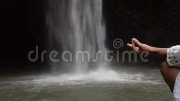 在热带瀑布坐坐冥想的女人视频的预览图