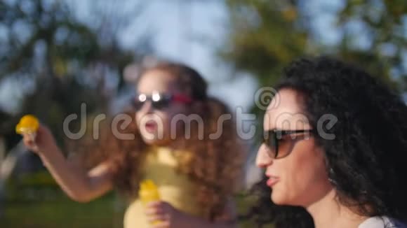 幸福微笑的家人妈妈和女儿正在玩耍在夏天的户外吹肥皂泡库存录像视频的预览图