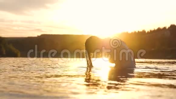 在热带小岛附近一个清爽的夏日傍晚嬉戏的女孩在清爽的河水中溅出长发视频的预览图