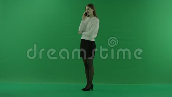 女孩站在她的左边在绿色的屏幕上讲电话视频的预览图