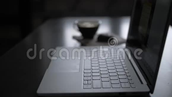 晚上桌旁的一个男人正在靠窗用笔记本电脑工作正在喝咖啡特写镜头视频的预览图