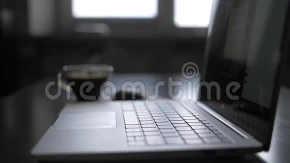 晚上工作一台笔记本电脑和一杯热咖啡蒸发在窗边的桌子上视频的预览图