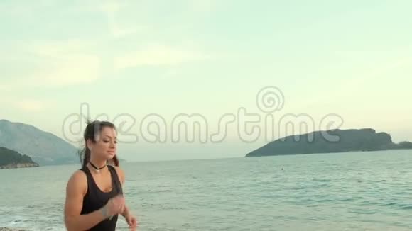 早上在海边海滩跑步的运动女人视频的预览图
