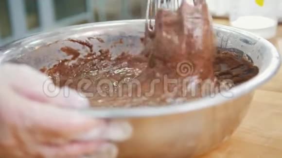 面包师把巧克力奶油混合在金属碗里视频的预览图