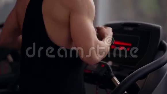 一个强壮的健美运动员在健身房锻炼时在跑步机上跑步的背面和侧面健康生活方式视频的预览图