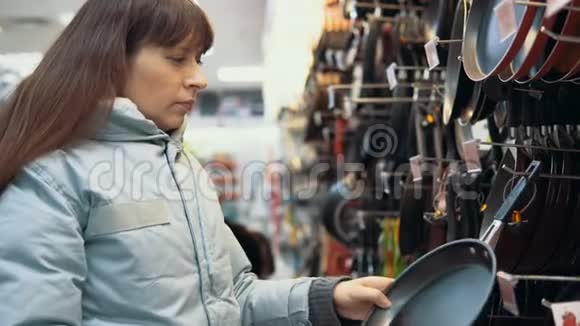 一个年轻的女人在商店里挑选一个平底锅视频的预览图
