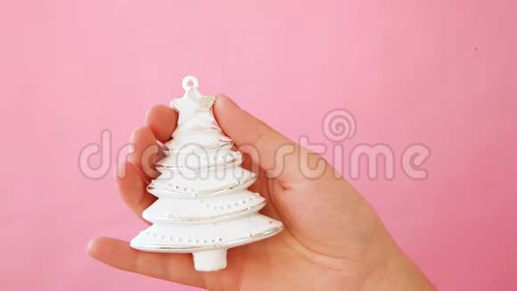简单的最小设计女性手拿圣诞装饰杉树隔离粉红色的粉彩色彩视频的预览图