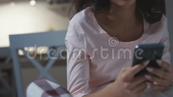 带着睡衣的美国黑人年轻女子微笑着在家打手机的画像视频的预览图