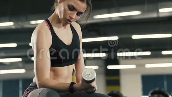 漂亮的年轻女孩在健身房背景下和哑巴一起做运动视频的预览图