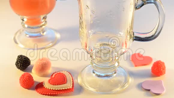果汁倒入两杯看不见边糖果和装饰心周围有选择的焦点视频的预览图