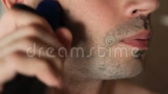 年轻人在浴室里用电动剃须刀刮胡子特写镜头那家伙在浴室里用剃刀刮胡子视频的预览图