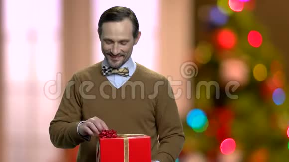 在圣诞背景上带着漂亮礼盒的男人视频的预览图