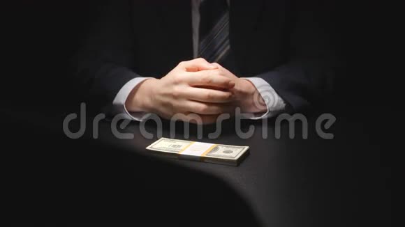 布里伯商人从一张桌子上拿出一捆钱在谈判时穿上西装美元视频的预览图
