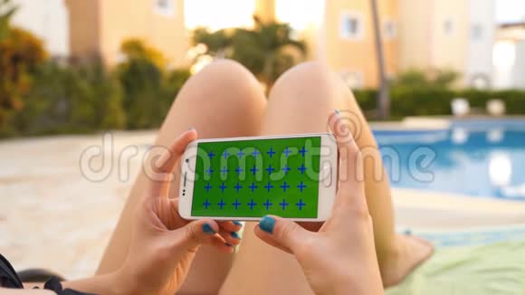 女人用手机在游泳池日光浴中放松视频的预览图