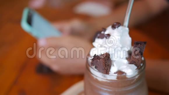 甜巧克力甜点奶油和年轻的女人看照片在智能手机在咖啡馆的背景视频的预览图