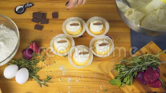 松饼上面放着奶油和巧克力片放在一张明亮的木桌上视频的预览图