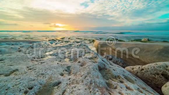 印度尼西亚巴厘岛海岸岩石海滩日落的美丽海洋时光视频的预览图