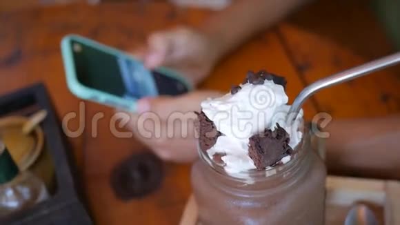 甜巧克力甜点与奶油和年轻妇女看图片在智能手机在咖啡馆的背景视频的预览图