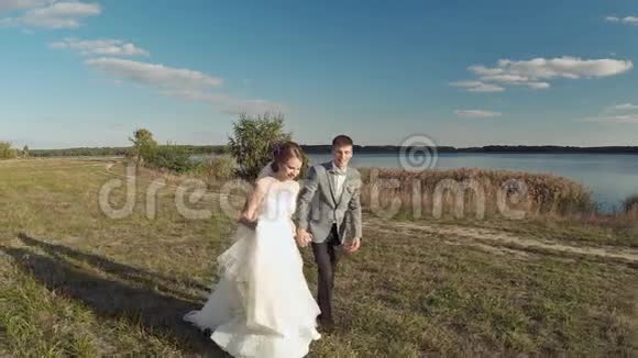 新郎和新娘跑空中射击傍晚的湖视频的预览图