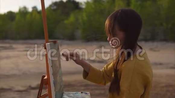 年轻漂亮的女画家画抽象的风景画视频的预览图