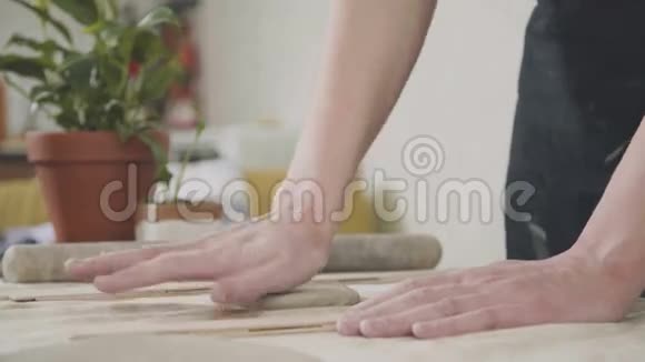女陶工在桌子上滚动陶粒粘土专用工具视频的预览图