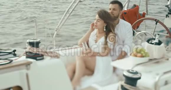恋爱中的情侣在游艇上放松穿着白色衣服的男人和女人彼此拥抱彼此温柔地享受着旅行视频的预览图
