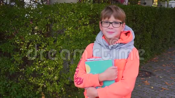 一个小学生的肖像他手里拿着一本教科书微笑着看着相机夏天结束了视频的预览图