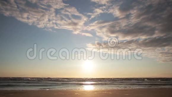 当海浪在阳光下闪闪发光时沙滩上美丽的日落视频的预览图