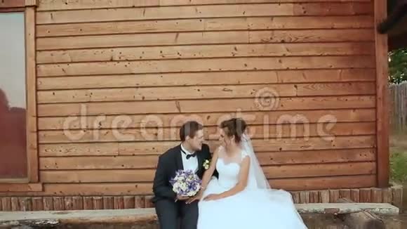新娘和新郎坐在老房子的长凳上浮动相机视频的预览图