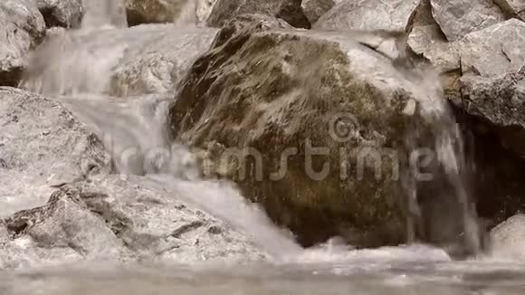 水流缓慢地在石头上落下溪流在石头上落下溅起小山视频的预览图