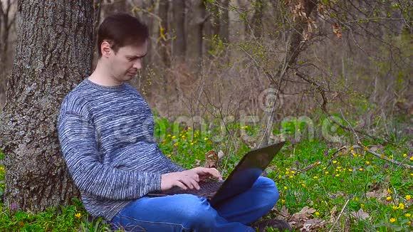 一个坐在笔记本电脑旁的男人在键盘上打字视频的预览图
