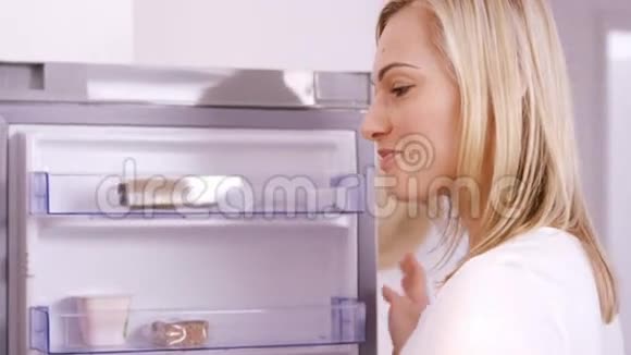 金发女人在冰箱上吃酸奶视频的预览图