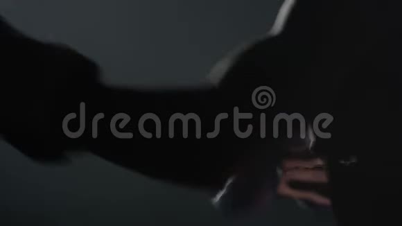 年轻的男拳击手在黑色背景上打拳在健身房里用红色拳击手套打孔袋MMA视频的预览图