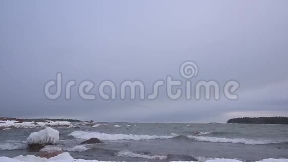 风暴般的波罗的海海浪在冰盖的岩石上翻滚视频的预览图