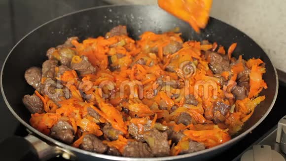 在煎锅里煎肉在煎锅里用胡萝卜炖肉把肉和胡萝卜混合在煎锅里视频的预览图