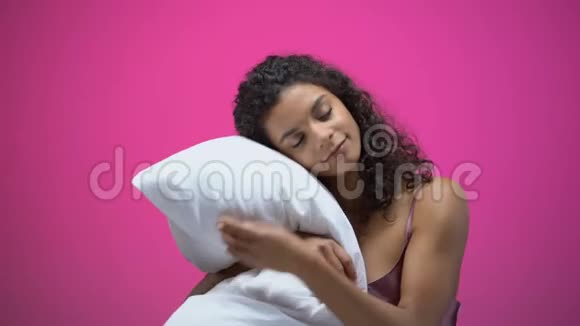 非洲裔美国妇女睡在粉红色背景的枕头上休息视频的预览图