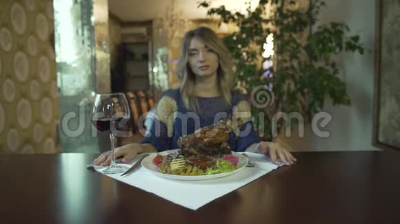 漂亮的金发碧眼的年轻女子在高档餐厅里用手等待着吃一大块炸肉视频的预览图