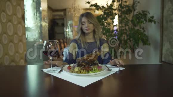 美丽的纹身金发女孩年轻的女人等待吃巨大的油炸肉手在高档餐厅视频的预览图