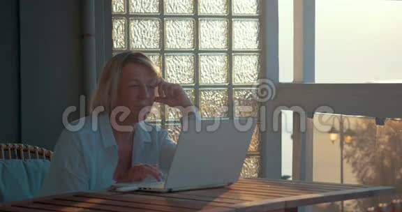 阳台上有笔记本电脑的成熟女人视频的预览图