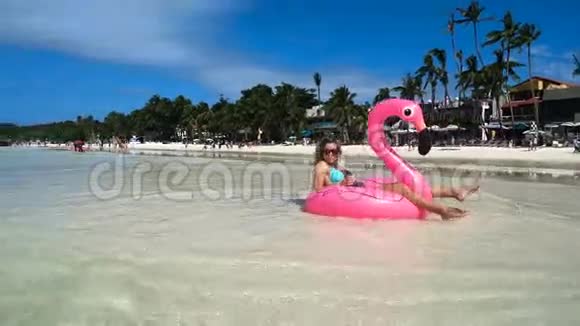 女孩漂浮在美丽的白色海滩上的充气床垫上上面有清澈的水视频的预览图