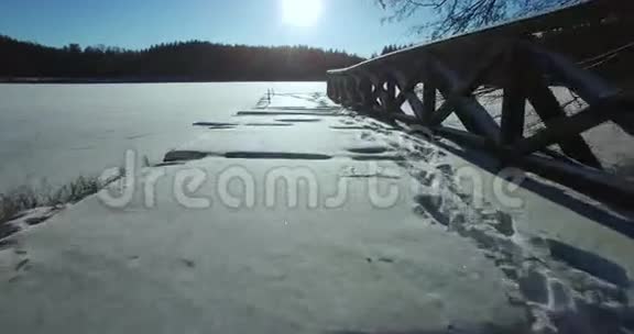 神圣的在非常寒冷美丽阳光明媚的冬日在立陶宛冰封的湖面上展开顺利取下木桥视频的预览图