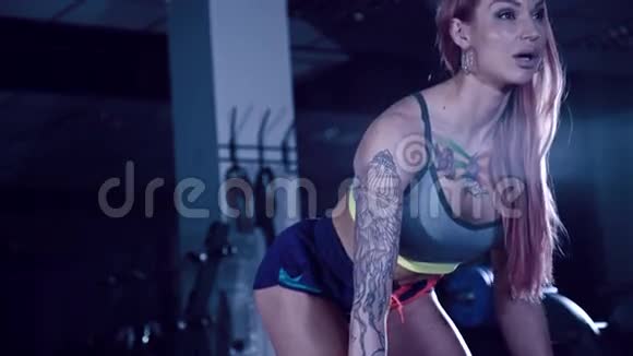 有纹身的运动女孩用杠铃做运动视频的预览图